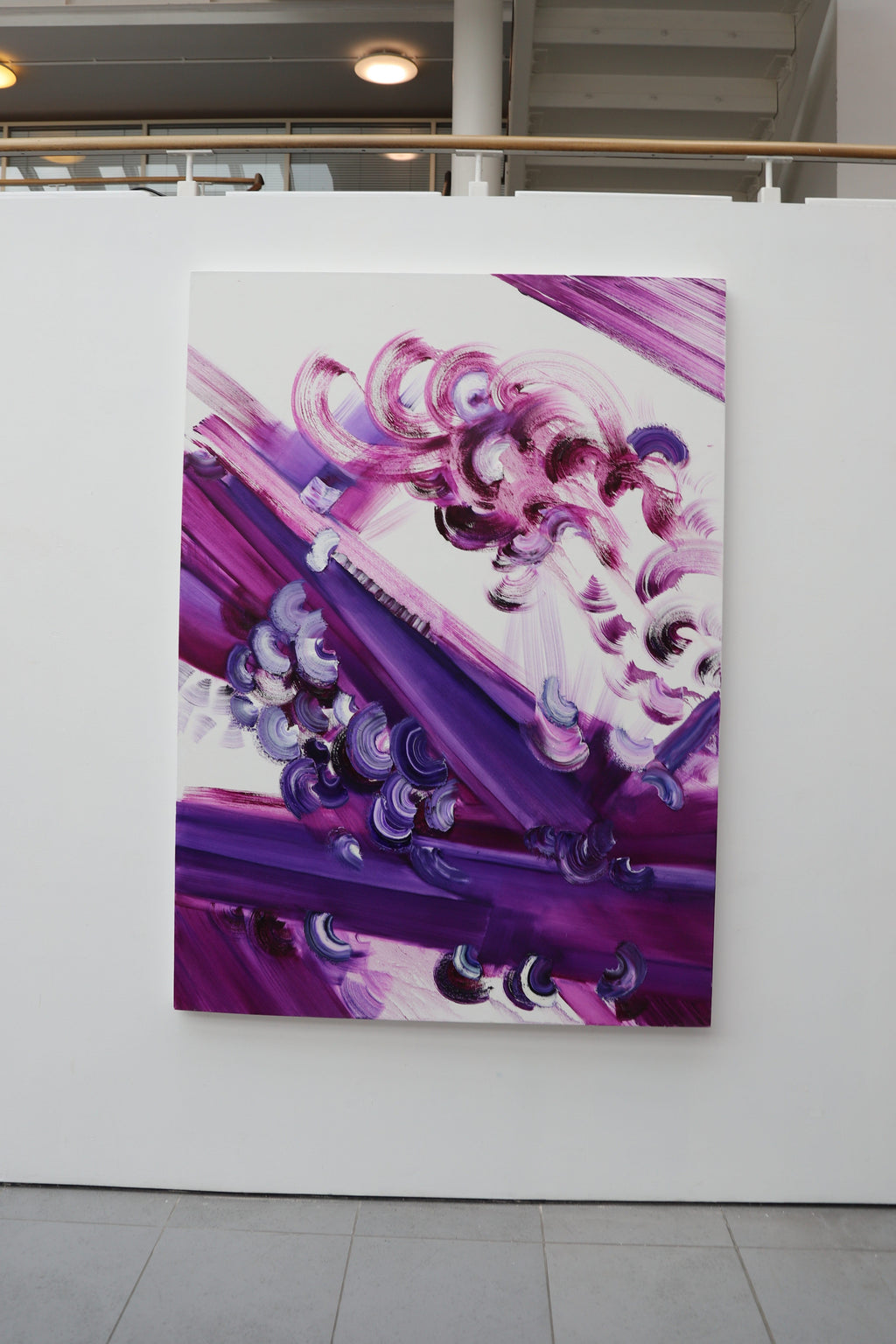 Abstract art piece with purple and pink colors on a white wall.