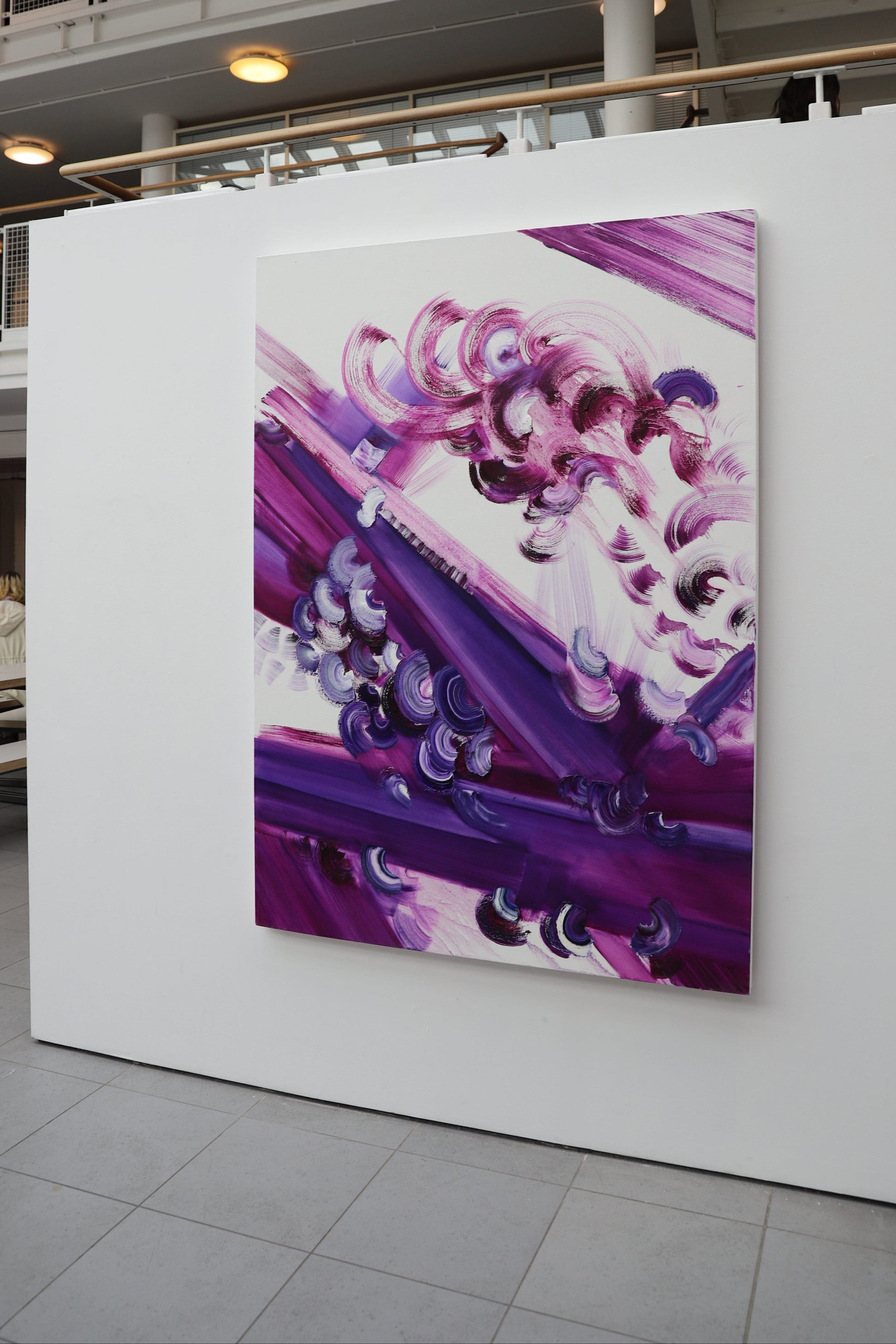Abstract painting with purple and pink tones on a white wall